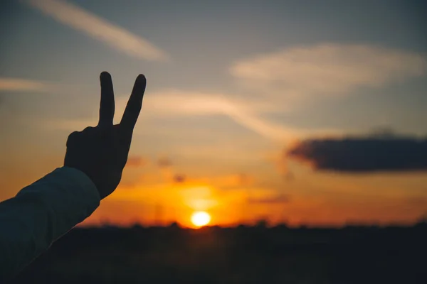 Mãos mostrar sinal de paz no pôr do sol — Fotografia de Stock