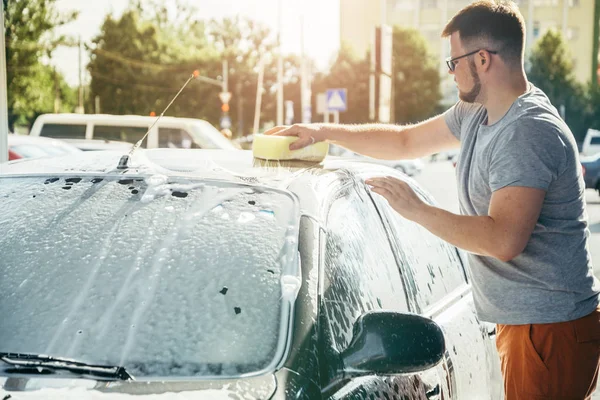 Człowiek woshing jego samochodu z gąbki — Zdjęcie stockowe