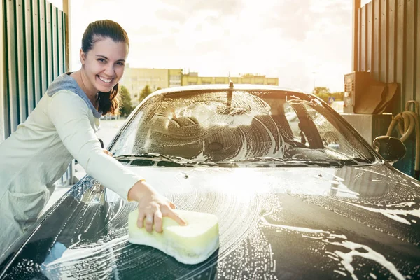 Jonge vrouw handen reinigen van de auto door de gele spons — Stockfoto