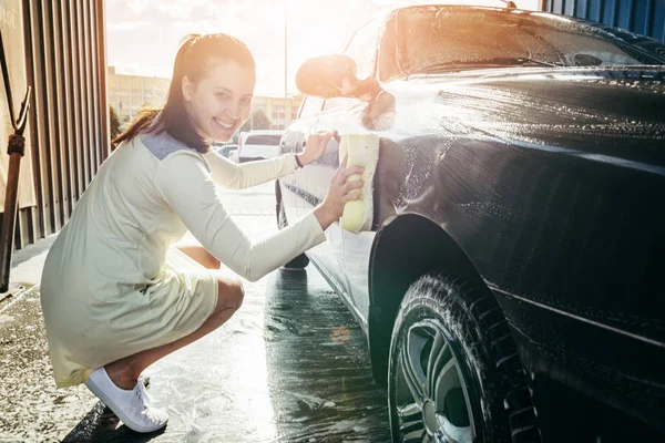 Joven mujer manos limpieza coche por amarillo esponja — Foto de Stock