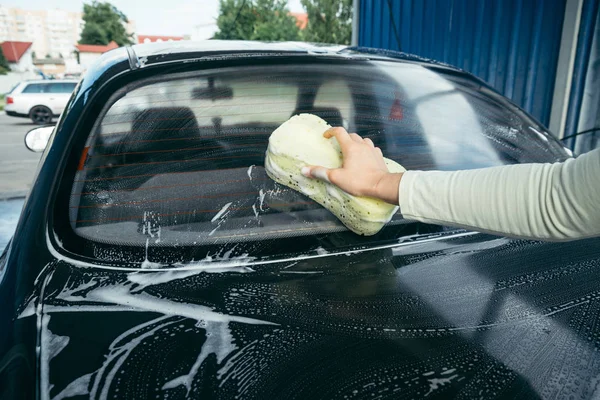 Uma mão lavando um carro com uma esponja — Fotografia de Stock