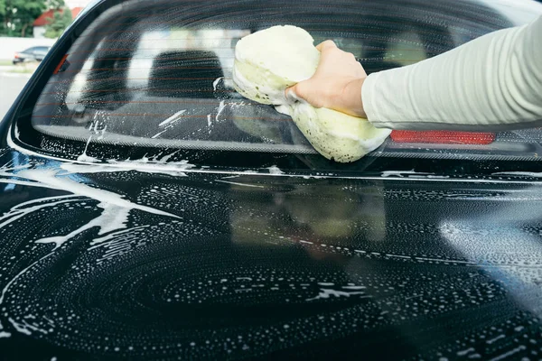 Una mano lavando un coche con una esponja — Foto de Stock