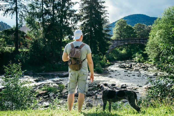 genç güçlü adam köpek ve görünümü için seyir ile dağlar Nehri yakınında kalacak