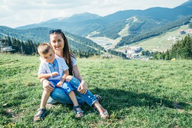 Anne ile oğlu dizlerinin üzerinde oturup dağları nın üstüne