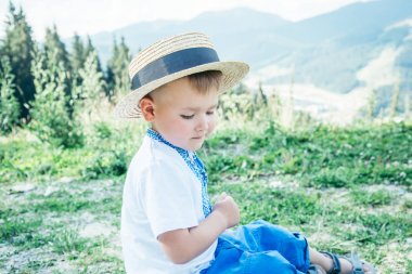 küçük çocuk yere dağların tepesinde oturan