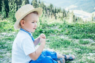 küçük çocuk yere dağların tepesinde oturan