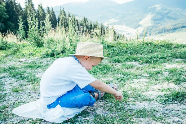 Μικρό αγόρι κάθεται στο έδαφος στις κορυφές των βουνών — Φωτογραφία Αρχείου