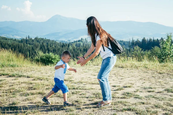 Mulher brincando com seu filho no pico da montanha — Fotografia de Stock