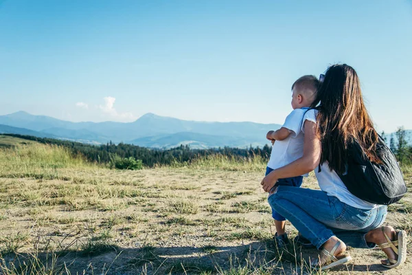 Mulher brincando com seu filho no pico da montanha — Fotografia de Stock
