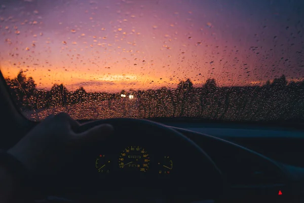 Kapka deště na pozadí skla auto s červený západ slunce — Stock fotografie