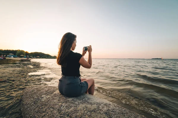 Frau sitzt am Strand und fotografiert das Meer — Stockfoto