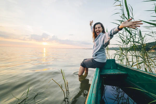 Young pretty woman sitting on the old bout and enjoying view of sunrise — Stock Photo, Image