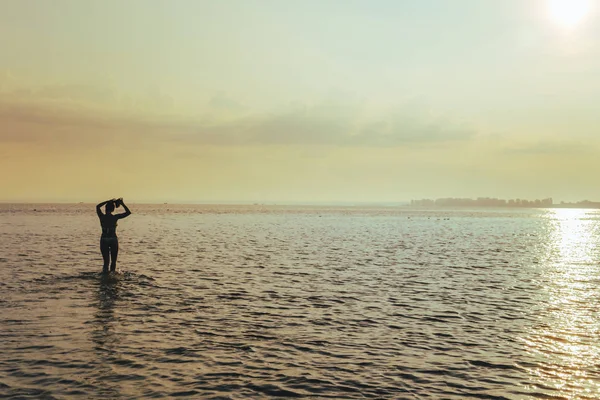 Mladá krásná žena při východu slunce ve vodě — Stock fotografie