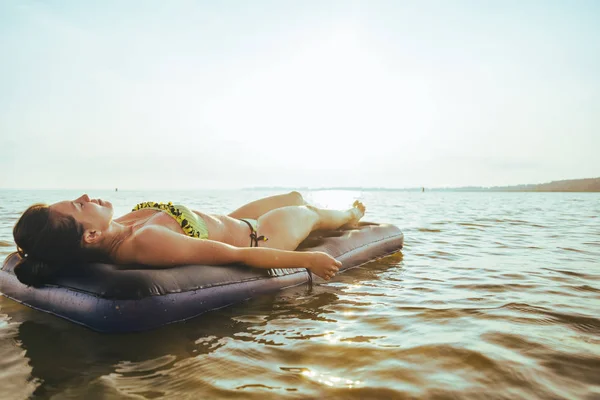 Vrouw krijgt tan liggend op een opblaasbare matras — Stockfoto