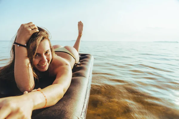 young pretty woman in bikini get suntan on inflatable mattress