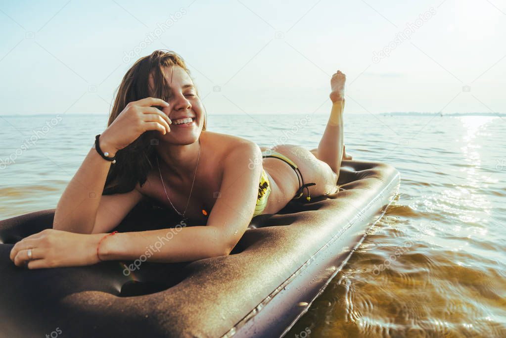 young pretty woman in bikini get suntan on inflatable mattress