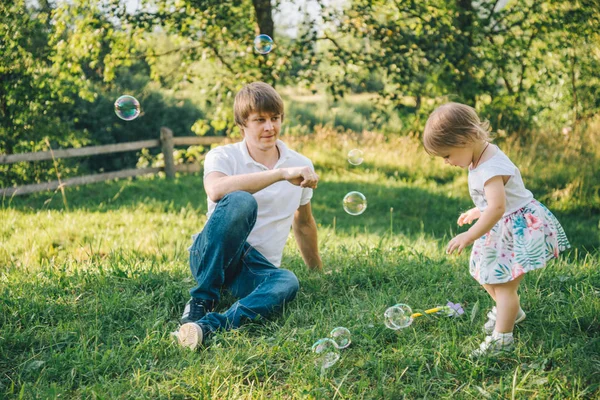 Батько грає зі своєю дочкою з мильною бульбашкою — стокове фото