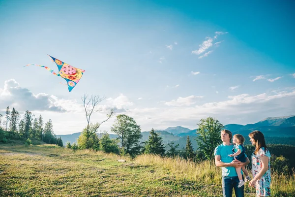 Famiglia che corre attraverso il campo lasciando volare aquilone — Foto Stock
