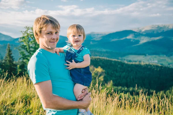 Padre e hija pequeña en sus manos en la cima de las montañas —  Fotos de Stock
