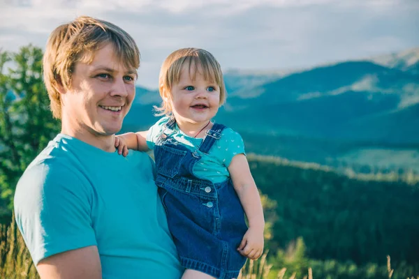 Батько і маленька дочка на руках на вершині гір — стокове фото