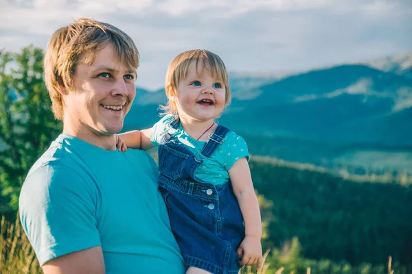 Батько і маленька дочка на руках на вершині гір — стокове фото