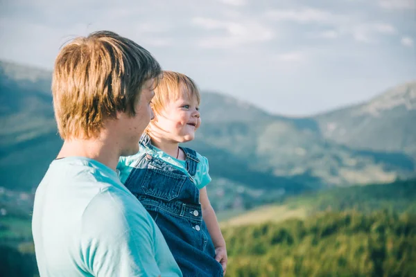 Baba ve küçük kız elindeki dağların tepesinde