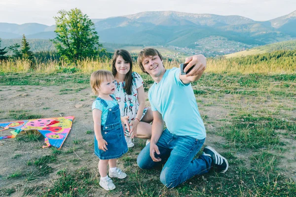 Щаслива молода сім'я бере селфі під час гри з повітряним змієм — стокове фото