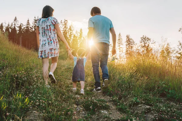 Madre y padre tomados de la mano de la hija y caminando por las montañas —  Fotos de Stock