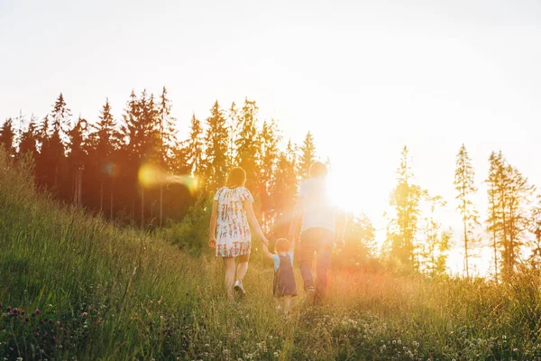 Madre y padre tomados de la mano de la hija y caminando por las montañas — Foto de Stock