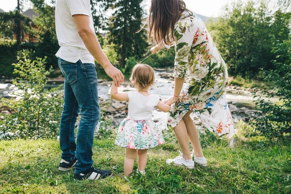 Щаслива родина грає з дочкою біля річки в горах — стокове фото