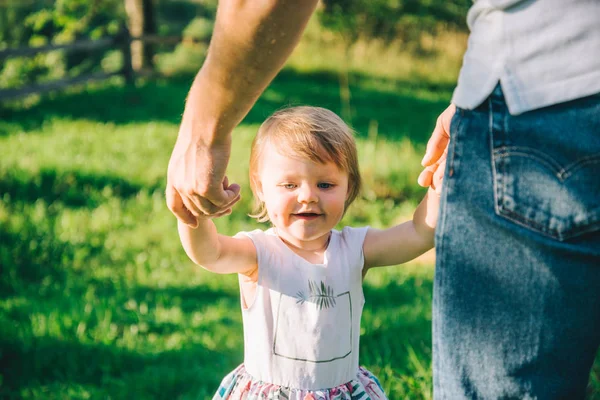 Фотограф тримає свою дочку за руки, допомагає їй ходити — стокове фото