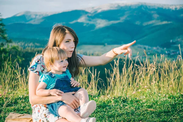 Mãe com a filha de joelhos apontam para algum lugar — Fotografia de Stock