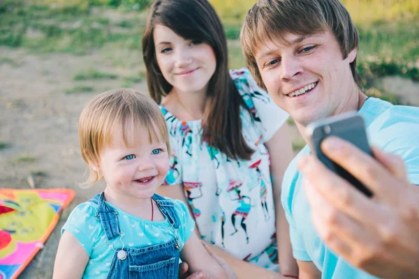 Feliz joven familia tomando selfie mientras jugando con cometa —  Fotos de Stock