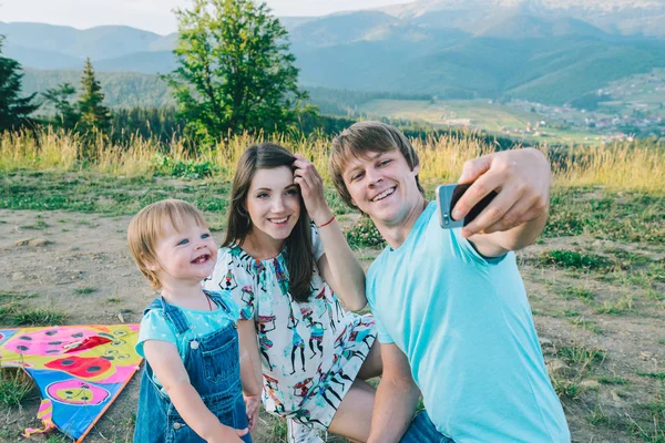 Feliz joven familia tomando selfie mientras jugando con cometa —  Fotos de Stock