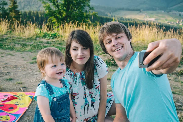 Feliz joven familia tomando selfie mientras jugando con cometa —  Fotos de Stock