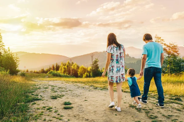 Madre y padre tomados de la mano de la hija y caminando por las montañas —  Fotos de Stock