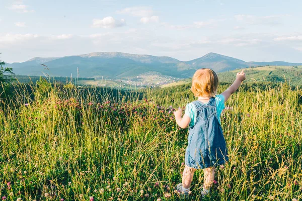 Маленька дівчинка стоїть на вершині і дивиться на гори — стокове фото