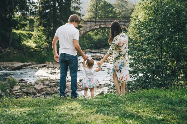 Щаслива родина грає з дочкою біля річки в горах — стокове фото