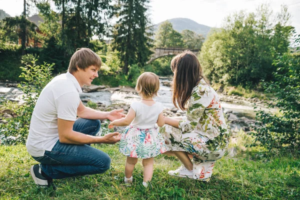 Feliz familia jugar con hija cerca del río en las montañas —  Fotos de Stock