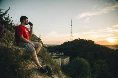 fincan kahve ile tepe üzerinde oturan adam
