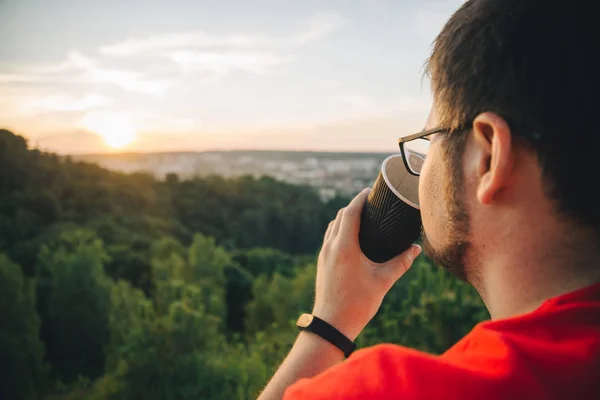 Muž sedí na vrcholu kopce s šálkem kávy — Stock fotografie