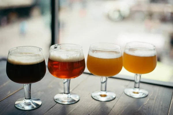 Quatro copos de cerveja na mesa de madeira — Fotografia de Stock