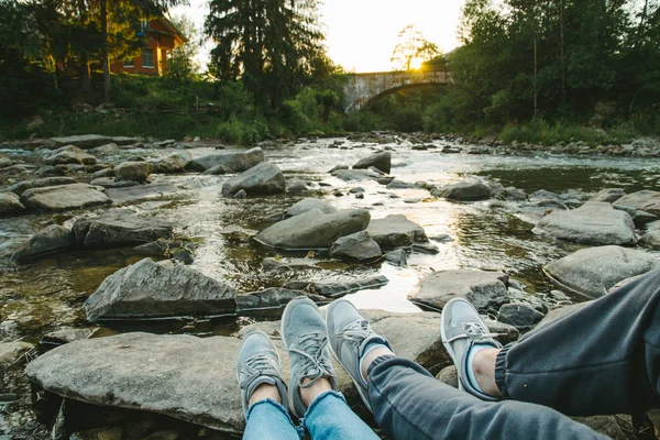 Cuplu stă lângă râul de munte și se uită la apus de soare — Fotografie, imagine de stoc