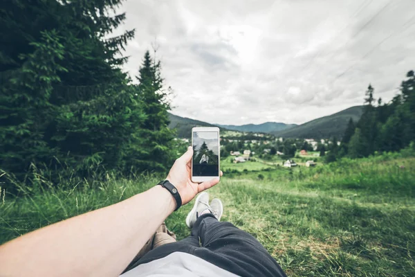 Hombre acostado en el suelo y tomando fotos de las montañas — Foto de Stock