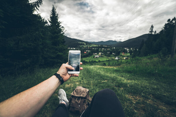 man lying on the ground and taking picture of mountains