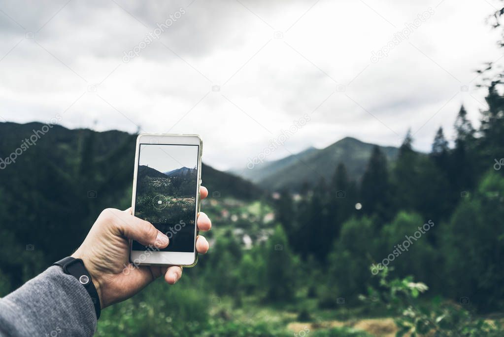 man taking picture of the mountains on his phone