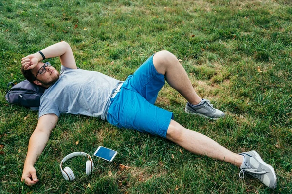 man lying on the grass listing music