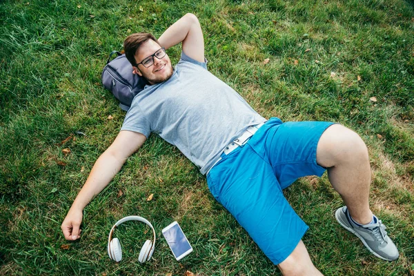 man lying on the grass listing music