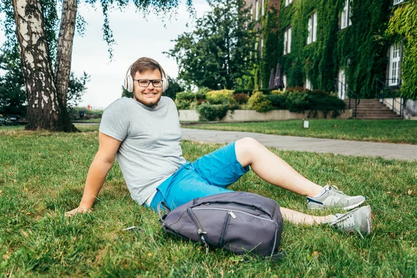 Mann sitzt im Stadtpark auf dem Boden und blickt auf Altbau — Stockfoto