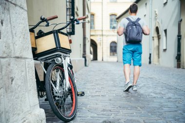 Eski Avrupa şehri sokak bisiklet tarafından yürüyen adam duvara yakın park